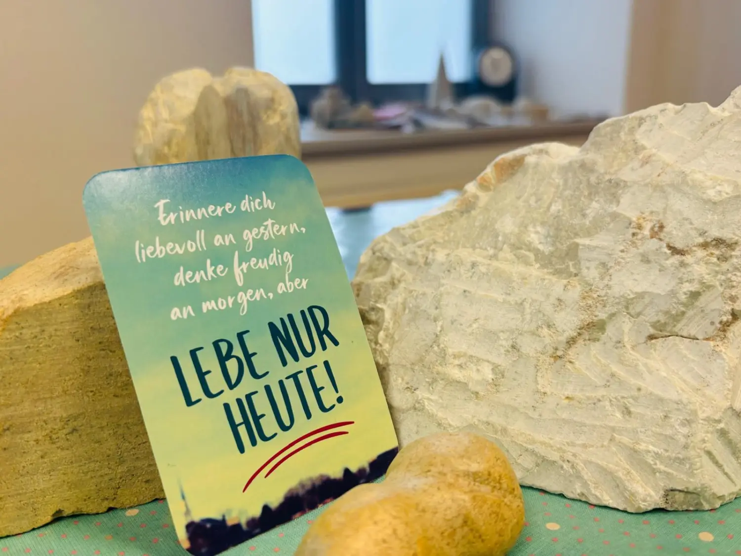 Sentio – eine dekorative Karte mit einem deutschen Motivationszitat, umgeben von natürlichen Gesteins- oder Mineralienproben