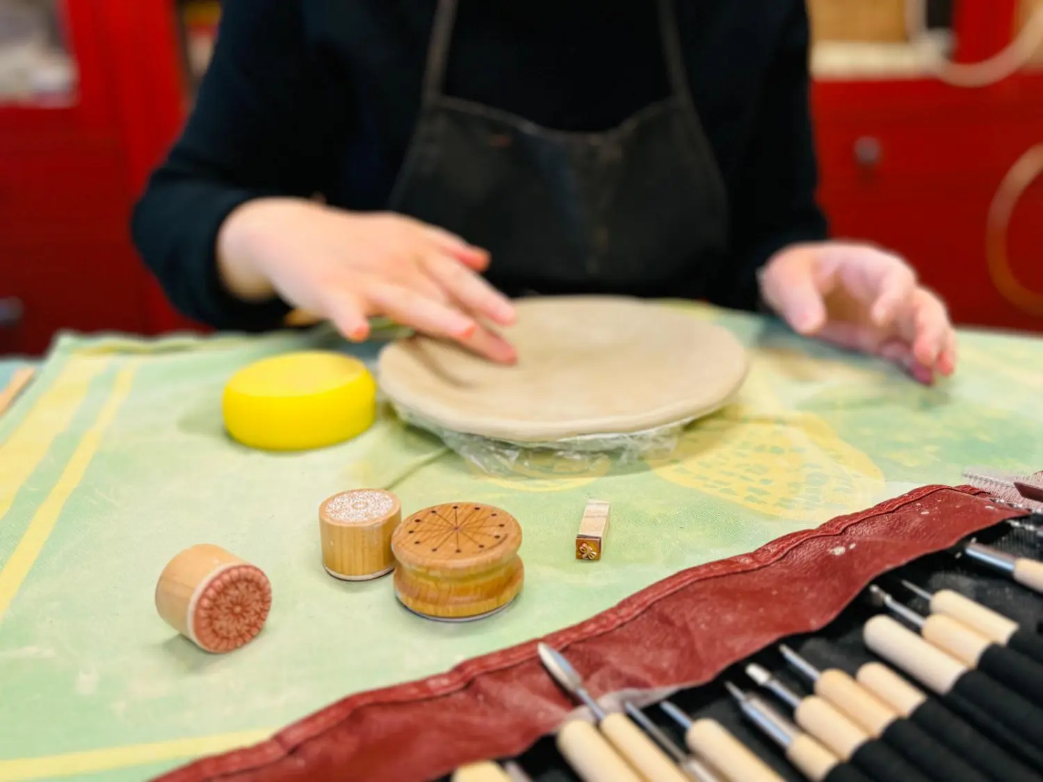 Sentio - eine Frau, die mit Ton arbeitet, während die Töpferwerkzeuge daneben auf dem Tisch liegen